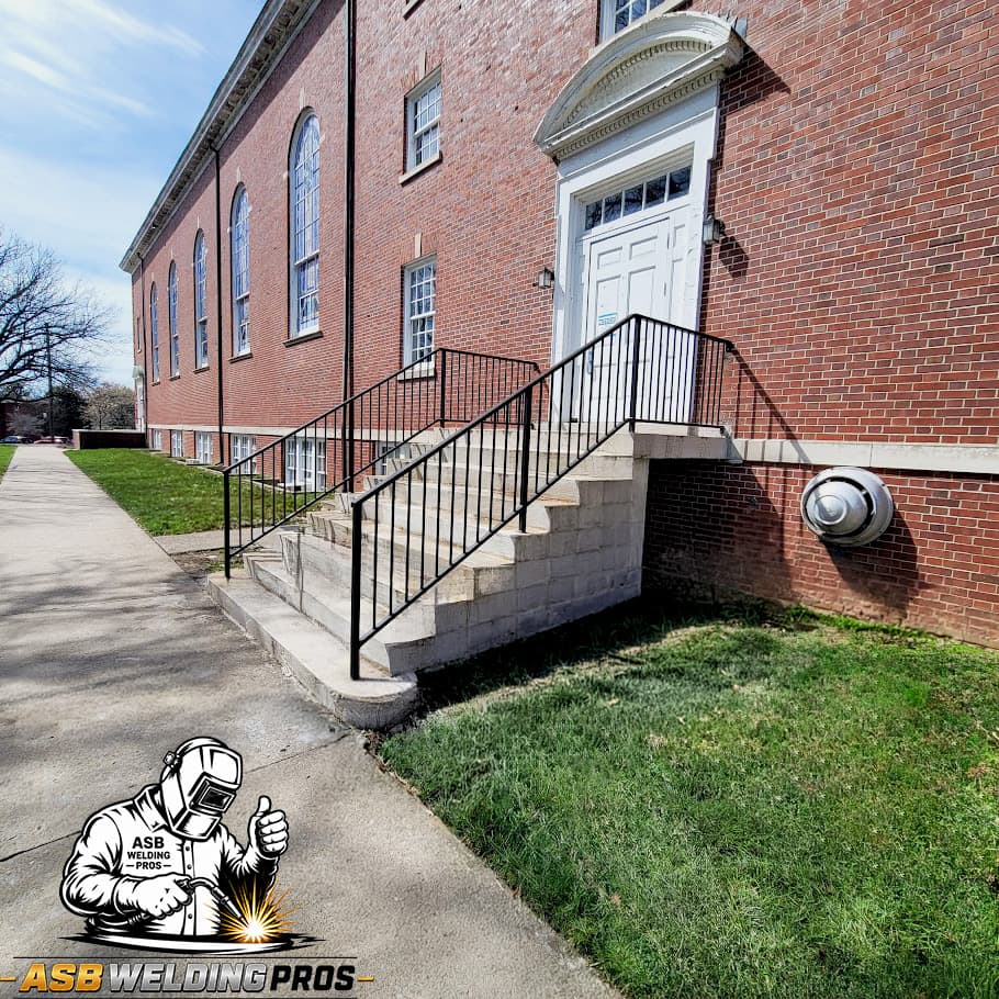 Black metal stair handrails installed at a brick commercial building.