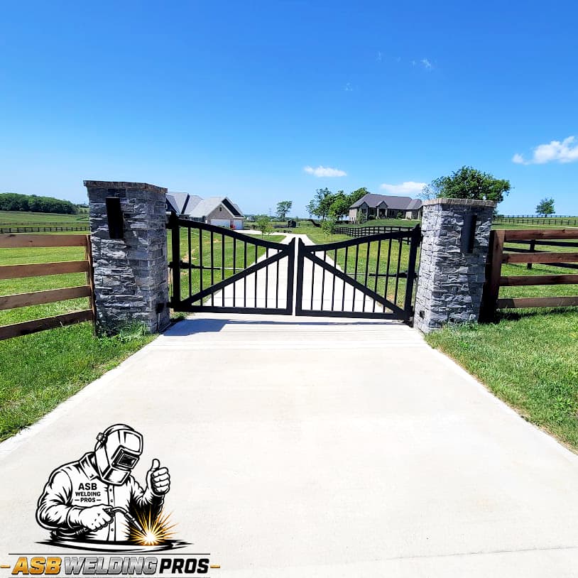 Black double driveway gate installed between stone columns in Central Kentucky.