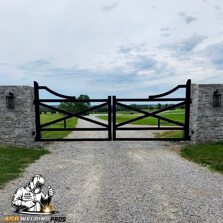 Black double-swing ranch gate spanning a gravel driveway.