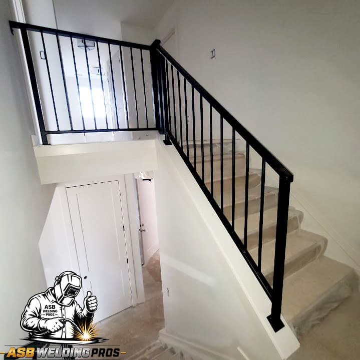 Black welded stair railing contrasting with a white residential stairwell.