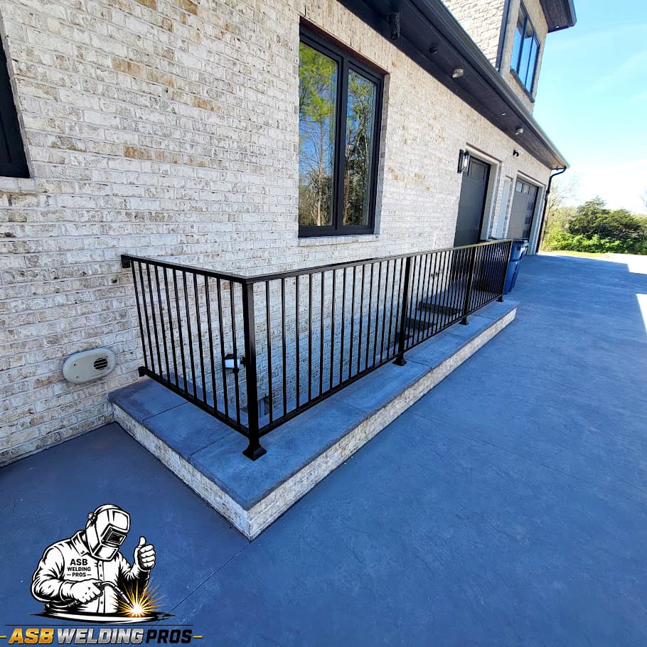 Black metal deck guardrail installed beside a white brick home.