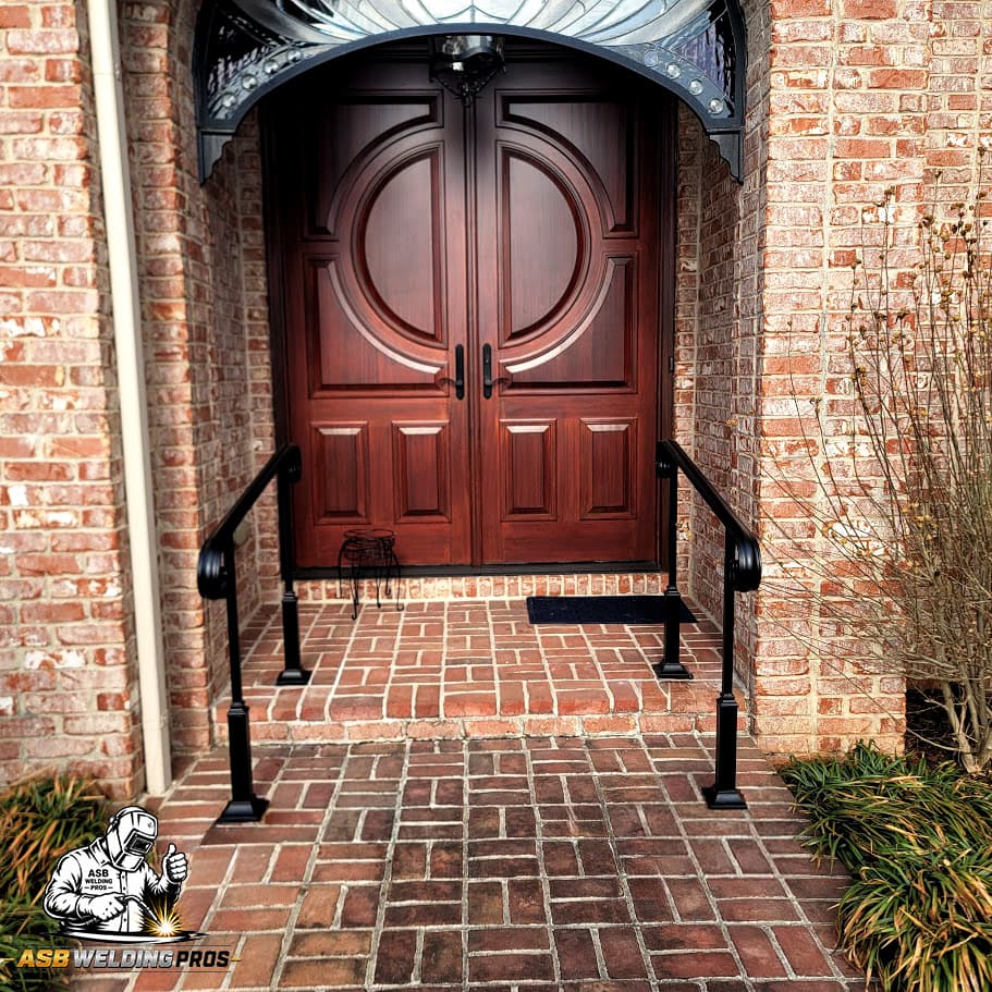 Paired black metal entry handrails installed at a brick home.