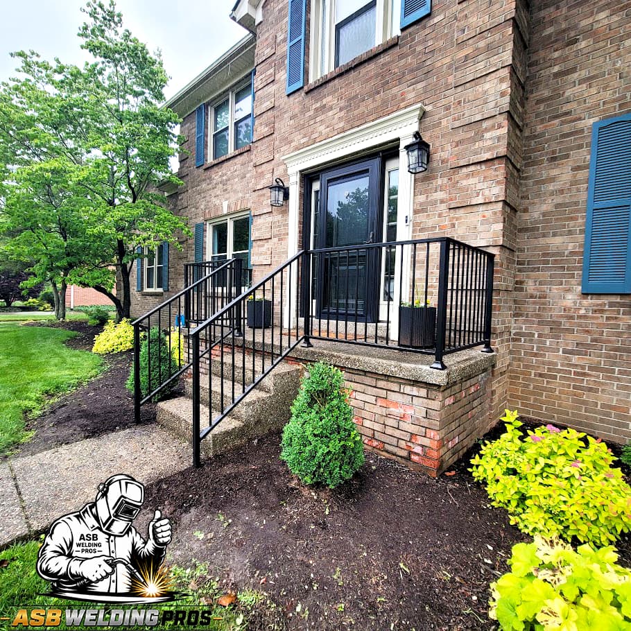 Black metal stoop railing installed at a brick home entrance.