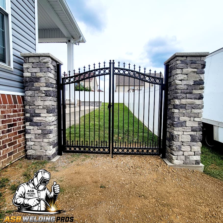 Ornamental black pedestrian gate installed between stone columns.