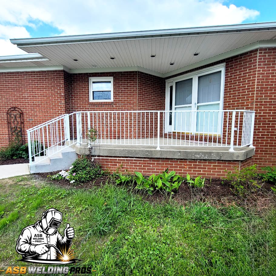 White metal porch guardrail installed around a brick home entry.