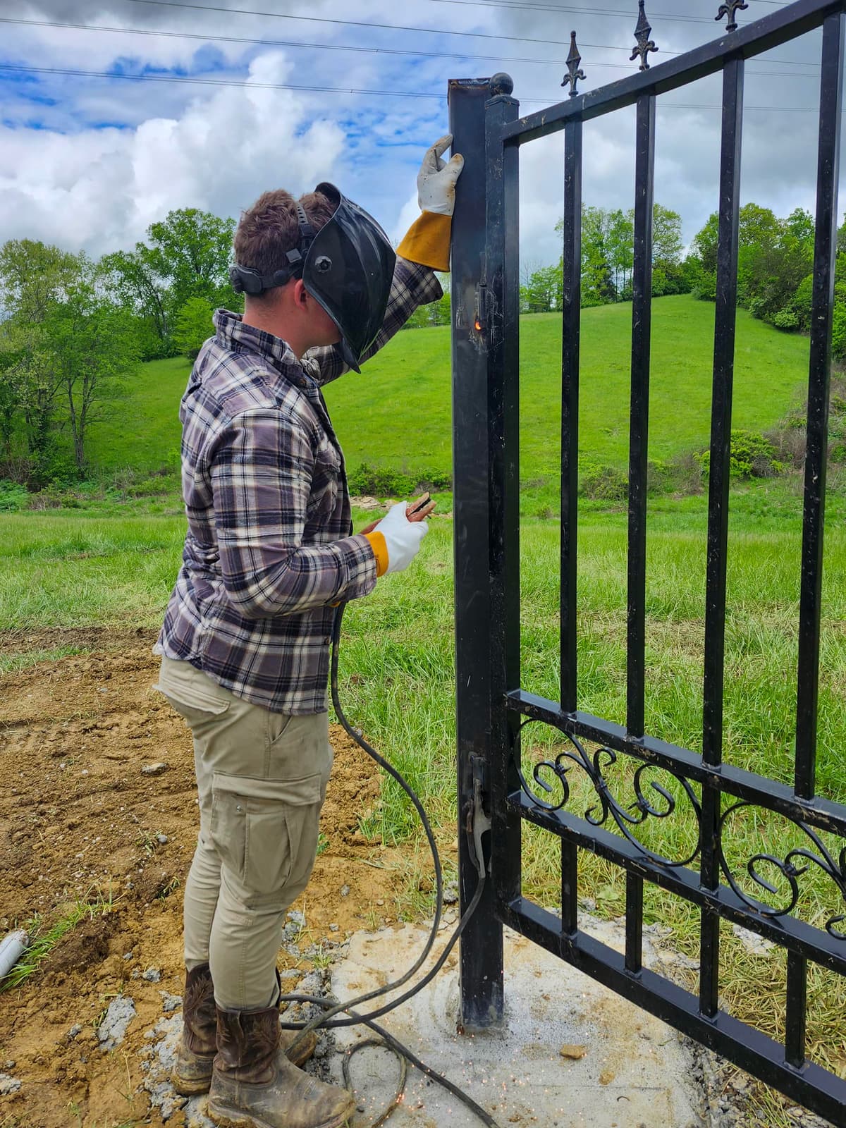 Custom black metal swing gate with wide driveway opening.