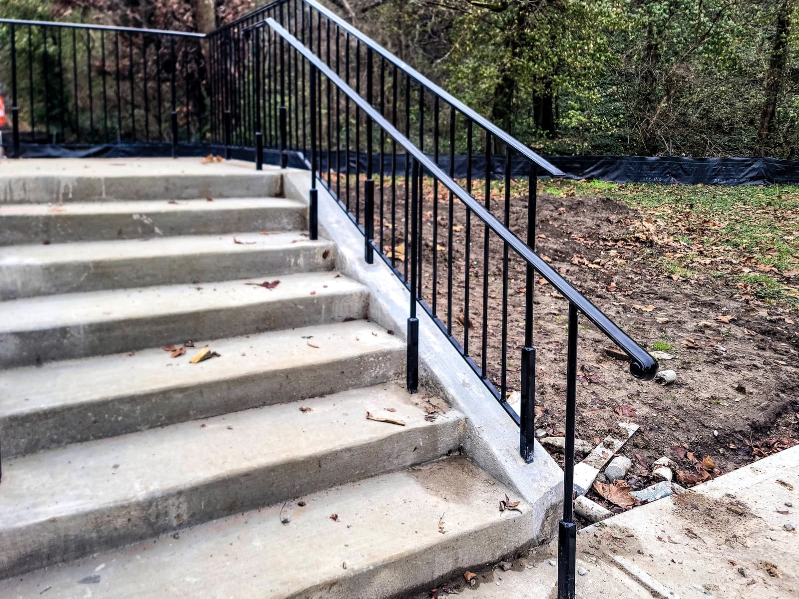 Commercial metal staircase railing coordinated with fence-line details.