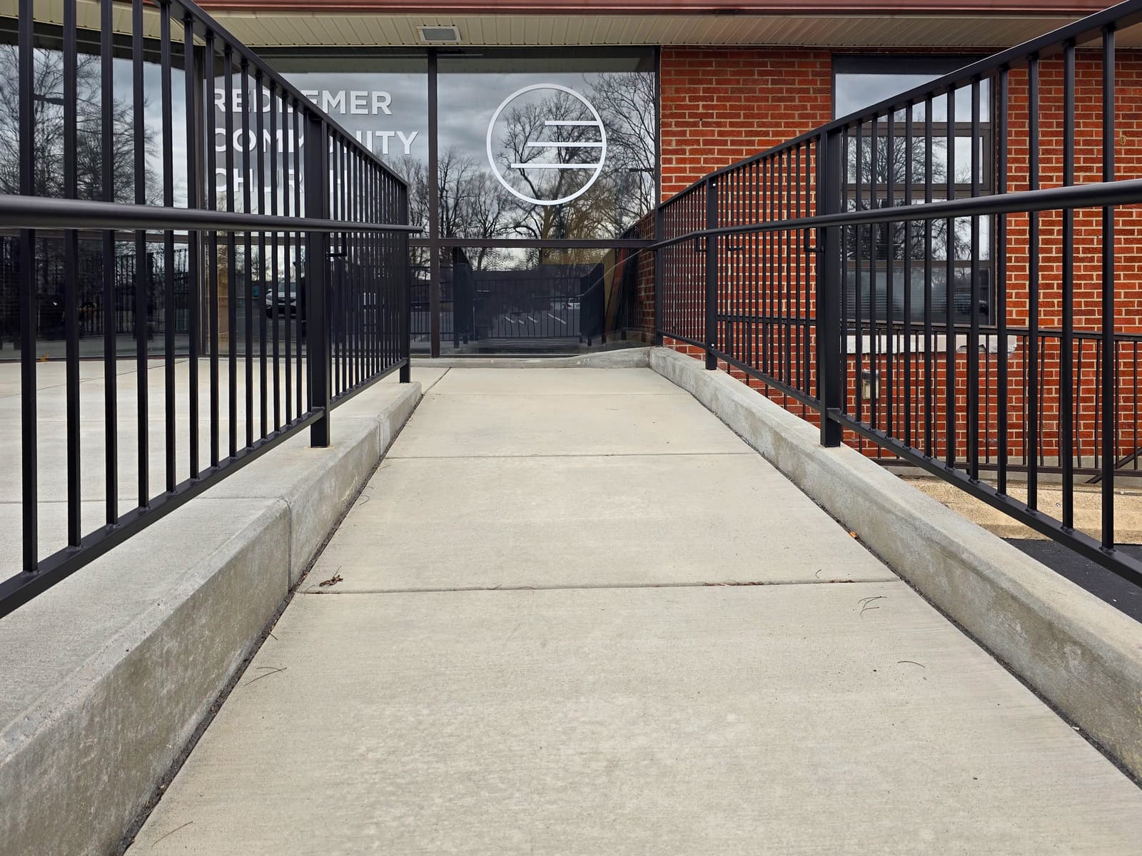 Close view of finished black metal guardrails along a commercial entrance ramp.