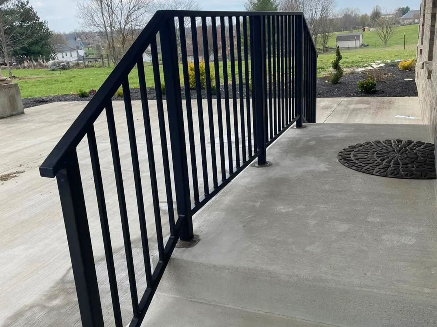 Finished metal porch railing installed along a residential walkway.