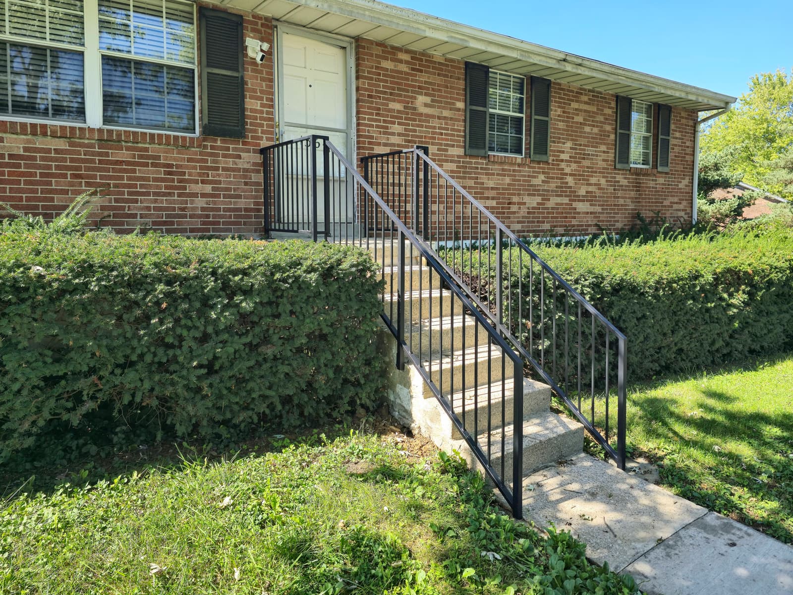 Metal step railing installed at a residential entry.